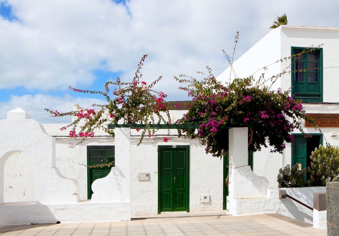Whitewashed house with green shutters and bougainvillea in Haría